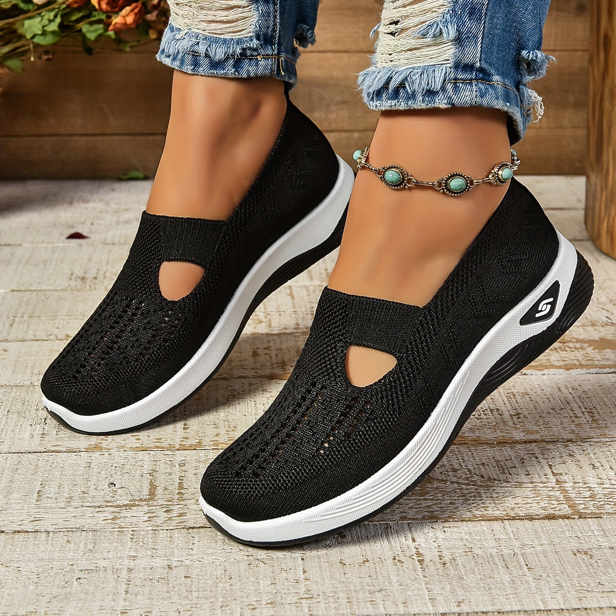 Chaussures noires Beatrix, portées avec jean, fond bois et fleurs